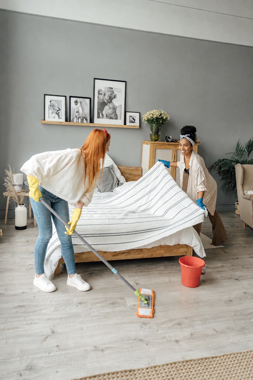 Two Wanderlust Cleaning team members making a bed and mopping the floor in a Denver home
